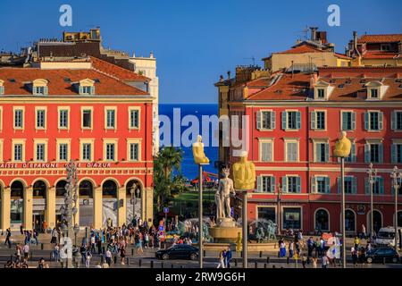 Nice, France - 29 mai 2023 : les touristes visitent la place Masséna principal monument commercial et culturel avec des bâtiments colorés ornés et la Fontaine du Soleil Banque D'Images