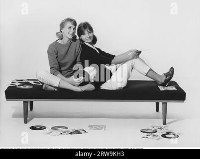 style de vie des années 1960. Deux filles dans des vêtements typiques des années 1960 sont assis ensemble tenant des disques de musique. Suède 1960 Banque D'Images