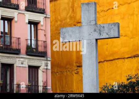 Gros plan sur une croix de pierre faite en 1738 contre un mur orange vif à la Plaza de Puerta Cerrada dans la vieille partie de Madrid en Espagne Banque D'Images