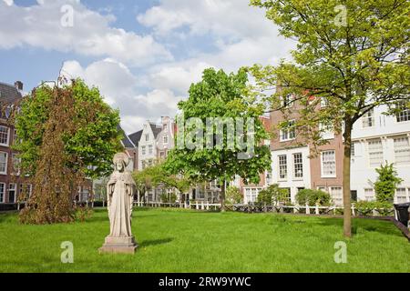 Cour Begijnhof avec statue de Jésus et jardin entouré de maisons historiques à Amsterdam, pays-Bas Banque D'Images
