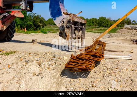 Les machines de chariot élévateur pour la livraison et le transport se préparent à soulever le paquet sélectionné d'armature rouillée du sol sur le chantier de construction. Banque D'Images