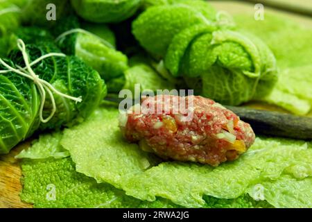 Une portion de viande hachée repose sur des feuilles de chou de savoie prêtes pour la préparation de rouleaux de chou de savoie Banque D'Images