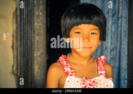 Srimongal, Bangladesh, vers juillet 2012 : jeune fille aux cheveux noirs courts vêtue de robe blanche et rouge sourit gentiment à la photo-caméra à Srimongal Banque D'Images