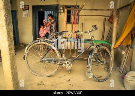 Srimongal, Bangladesh, vers juillet 2012 : photo d'un vieux vélo noir dans un abri à Srimongal, Bangladesh. En arrière-plan avec femme et petit enfant. Banque D'Images