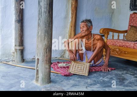 Srimongal, Bangladesh, vers juillet 2012 : un vieil homme mince est assis sur une couverture à damier sur le sol et regarde vers la gauche à Srimongal, Bangladesh. Documentaire Banque D'Images