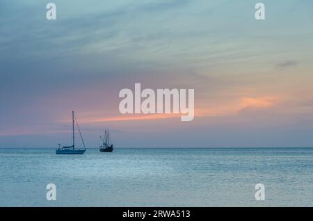Voiliers sur la mer naviguant sous le coucher du soleil. L'image a été prise de Palm Beach à Aruba, dans la mer des Caraïbes Banque D'Images