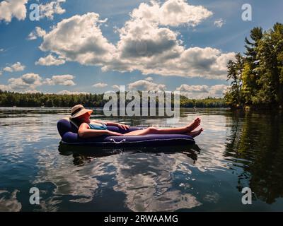 Femme en maillot de bain flottant sur la chaise gonflable sur le lac en été. Banque D'Images