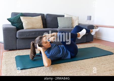 Femme travaillant à la maison faisant des Crunches de vélo Banque D'Images