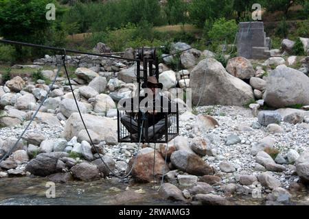 Homme traversant une rivière dans une poulie tirée à la main, Himalaya, Himachal Pradesh, Inde Banque D'Images