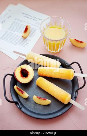 Sucettes glacées à la pêche avec des pêches fraîches et un verre de jus d'orange Banque D'Images
