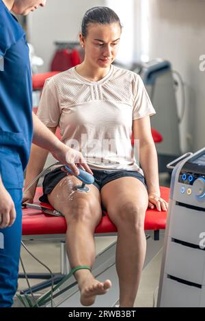 Médecin utilisant une machine pour traiter les articulations du genou d'un patient. Banque D'Images