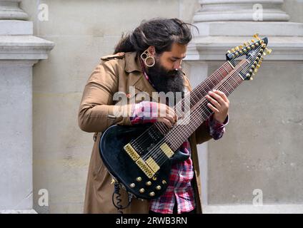 Londres, Royaume-Uni. Busker à Trafalgar Square jouant une guitare électrique à 16 cordes Banque D'Images