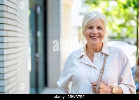 Portrait de femme âgée heureuse debout dans la ville Banque D'Images