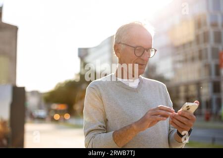 Homme senior utilisant smartphone dans la ville Banque D'Images