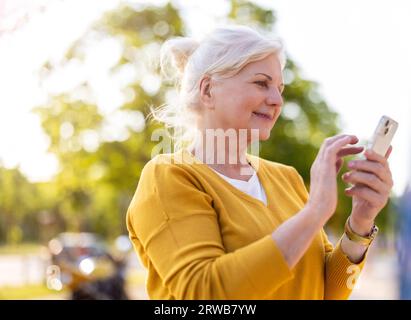 Senior woman using smartphone outdoors Banque D'Images