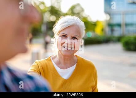 Portrait de couple senior heureux debout dans la rue de la ville par une journée ensoleillée Banque D'Images
