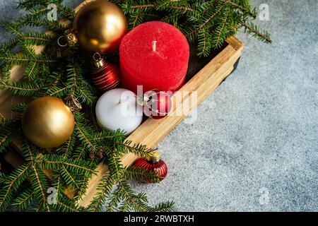 D'en haut des boules de Noël bougies et planche de bois placée sur la surface grise près des branches de sapin vert Banque D'Images