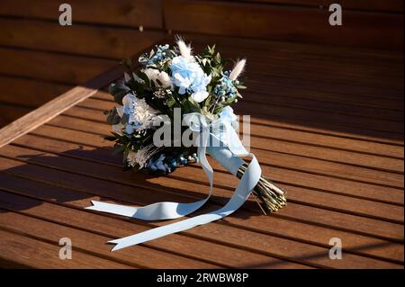 Beau bouquet de mariage délicat avec des fleurs bleues et blanches et des plantes vertes décoratives sur la table en bois Banque D'Images