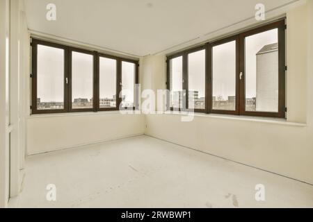Intérieur de chambre vide spacieuse avec de grandes fenêtres et des murs blancs avec sol stratifié dans un appartement moderne Banque D'Images
