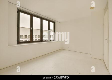 Intérieur de chambre vide avec de grandes fenêtres lumineuses et des murs blancs avec porte fermée dans un appartement rénové contemporain Banque D'Images