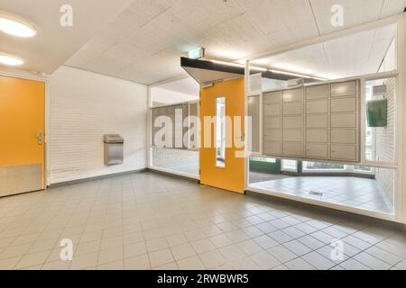 Intérieur de la chambre spacieuse vide avec porte jaune entre les casiers intégrés dans la fenêtre avec sol carrelé à l'intérieur de l'immeuble de bureaux moderne Banque D'Images