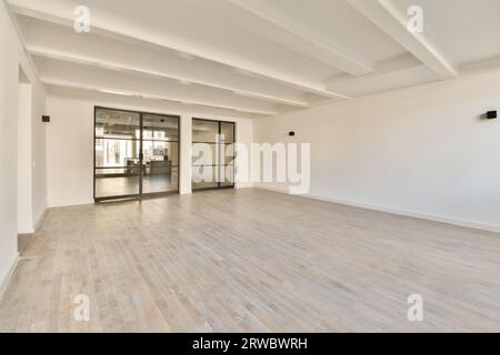 Intérieur de chambre vide spacieuse avec de grandes portes vitrées et des murs blancs avec sol stratifié dans un appartement moderne Banque D'Images