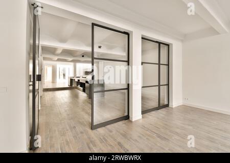 Intérieur de salon spacieux avec de grandes portes vitrées et des murs blancs et sol stratifié dans un appartement moderne Banque D'Images