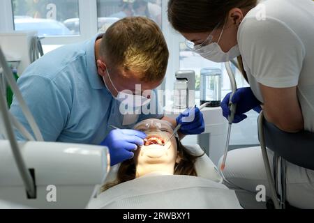 dernière technologie de nettoyage et de blanchiment des dents infirmière et médecin traitant les dents d'une jeune patiente adolescente masque gants propreté hygiène. dispositif dernier cri en cabinet dentaire en clinique Banque D'Images