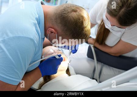 dernière technologie de nettoyage et de blanchiment des dents infirmière et médecin traitant les dents d'une jeune patiente adolescente masque gants propreté hygiène. dispositif dernier cri en cabinet dentaire en clinique Banque D'Images