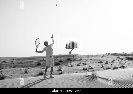 Homme jouant au tennis sur un barkhan dans le désert. Photo de haute qualité Banque D'Images