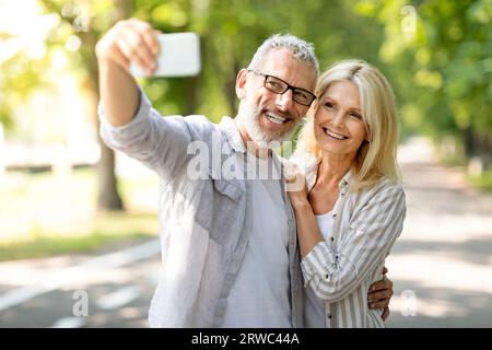 Heureux couple mature ayant du plaisir tout en prenant Selfie sur smartphone à l'extérieur Banque D'Images