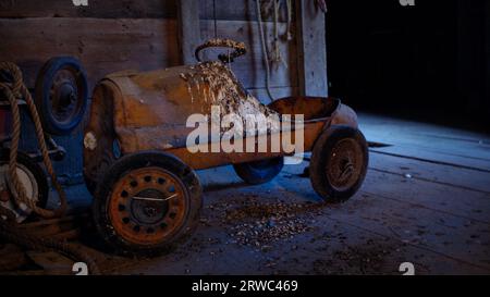 Voiture à pédales vintage, abandonnée et longtemps oubliée et négligée dans une ancienne grange à foin dans l'Iowa. Banque D'Images