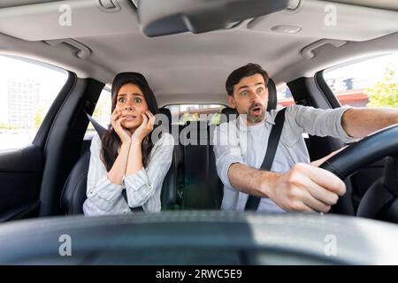 Couple choqué dans l'automobile regardant la route avec des visages choqués Banque D'Images