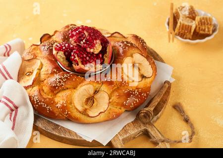 Fêtes juives - Rosh Hashana ou Rosh Hashana. Grenade, pommes, miel et challah rond sur fond de table jaune rustique. Célébration d'automne juif Banque D'Images