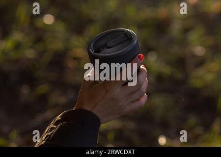 Les mains féminines tiennent une tasse à café réutilisable. Mode de vie durable. Concept respectueux de l'environnement. Banque D'Images