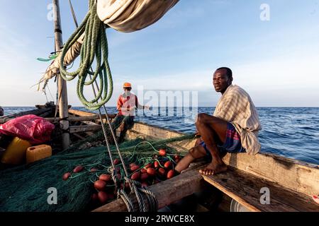 Dar es Salaam, Tanzanie - mars 2023 : des pêcheurs locaux pêchent sur un vieux bateau. Banque D'Images