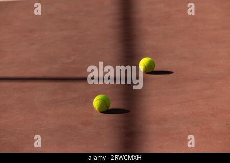 Balle de tennis sur terrain de terre battue deux séparés par l'ombre Banque D'Images