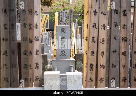 Marqueur tombeau de style bouddhiste traditionnel entouré de planches de bois appelées sotoba au petit cimetière attaché au temple bouddhiste zen Tengen-ji, dans le district de Yanaka, Taito City, Tokyo, Japon. Banque D'Images