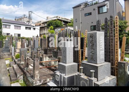 Marqueur tombeau de style bouddhiste traditionnel entouré de planches de bois appelées sotoba au petit cimetière attaché au temple bouddhiste zen Tengen-ji, dans le district de Yanaka, Taito City, Tokyo, Japon. Banque D'Images