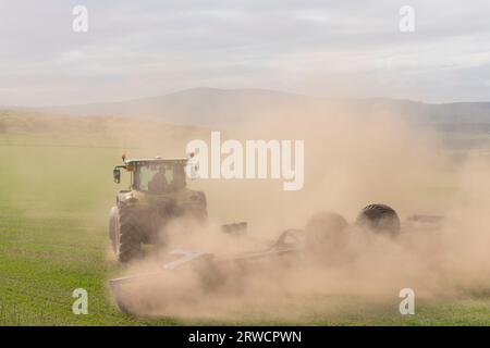 Nuages de poussière par temps sec d'un tracteur avec rouleaux Dal-Bo tournant dans un champ tout en roulant une récolte d'orge de printemps Banque D'Images