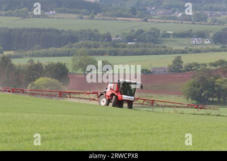 Un pulvérisateur de cultures Bateman 4000 tournant dans un champ tout en pulvérisant une récolte d'orge de printemps dans la campagne de l'Aberdeenshire Banque D'Images