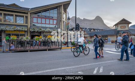 Canmore, Alberta, Canada – le 16 septembre 2023 : les gens marchent et font du vélo sur la rue main dans la lumière du soir Banque D'Images
