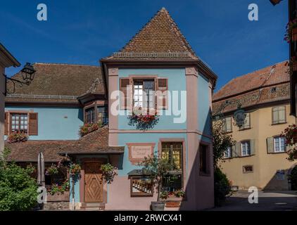 Hunawihr, France - 09 04 2023 : vue sur la façade d'un restaurant bleu et rose typique avec des fleurs suspendues Banque D'Images