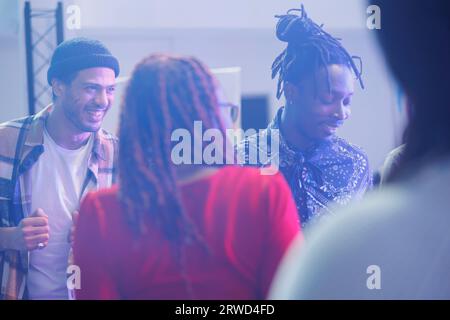 Groupe d'amis souriants et joyeux socialisant et faisant la fête dans la boîte de nuit. Insouciante personnes diverses dansant et bavardant sur dancefloor tout en clubbing à l'événement de rassemblement social Banque D'Images