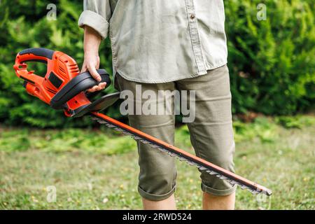 Femme jardinier tenant taille-haie électrique. La personne méconnaissable est prête pour la coupe à l'arrière-cour. Matériel de jardinage Banque D'Images