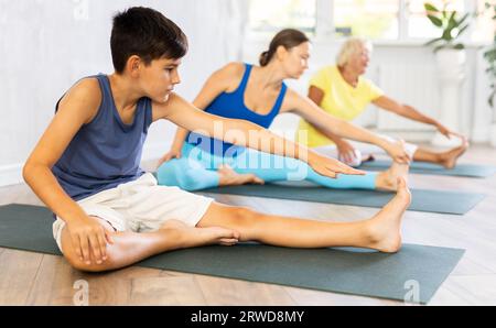 La mère, la grand-mère et le fils adolescent exercent Janu Shirshasana pose. Banque D'Images