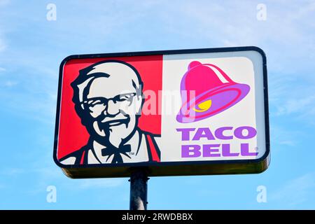 Gros plan d'un panneau annonçant Kentucky Fried Chick et Taco Bell contre un beau ciel bleu. Banque D'Images