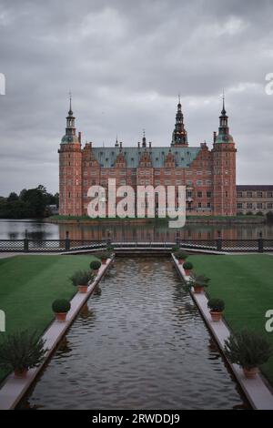 Château de Frederiksborg à Hillerød Danemark, vue depuis le jardin baroque au coucher du soleil avec des nuages sombres Banque D'Images