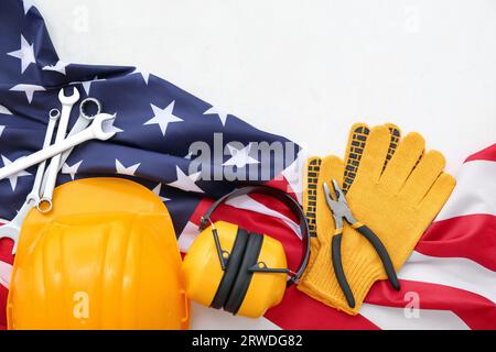 Équipement de protection, outils et drapeau américain sur fond blanc. Célébration de la fête du travail Banque D'Images