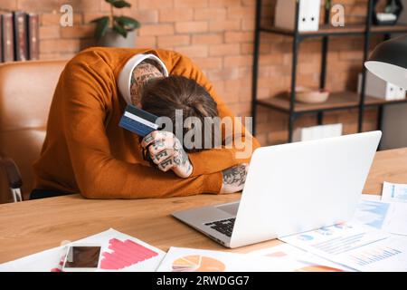 Jeune homme avec carte de crédit à table dans le bureau Banque D'Images